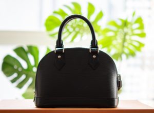 Handbag Sitting On Table With Green Leaves Behind It