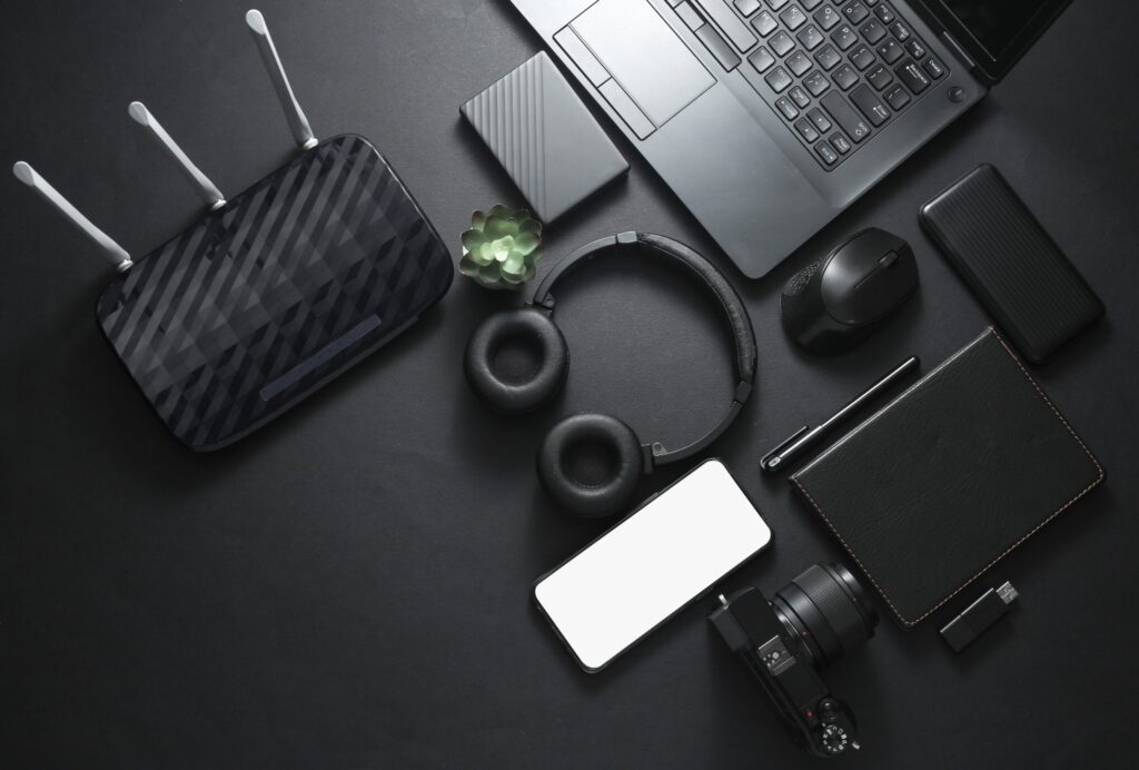 Laptop, camera, headphones, smartphone and other electronics on a dark surface